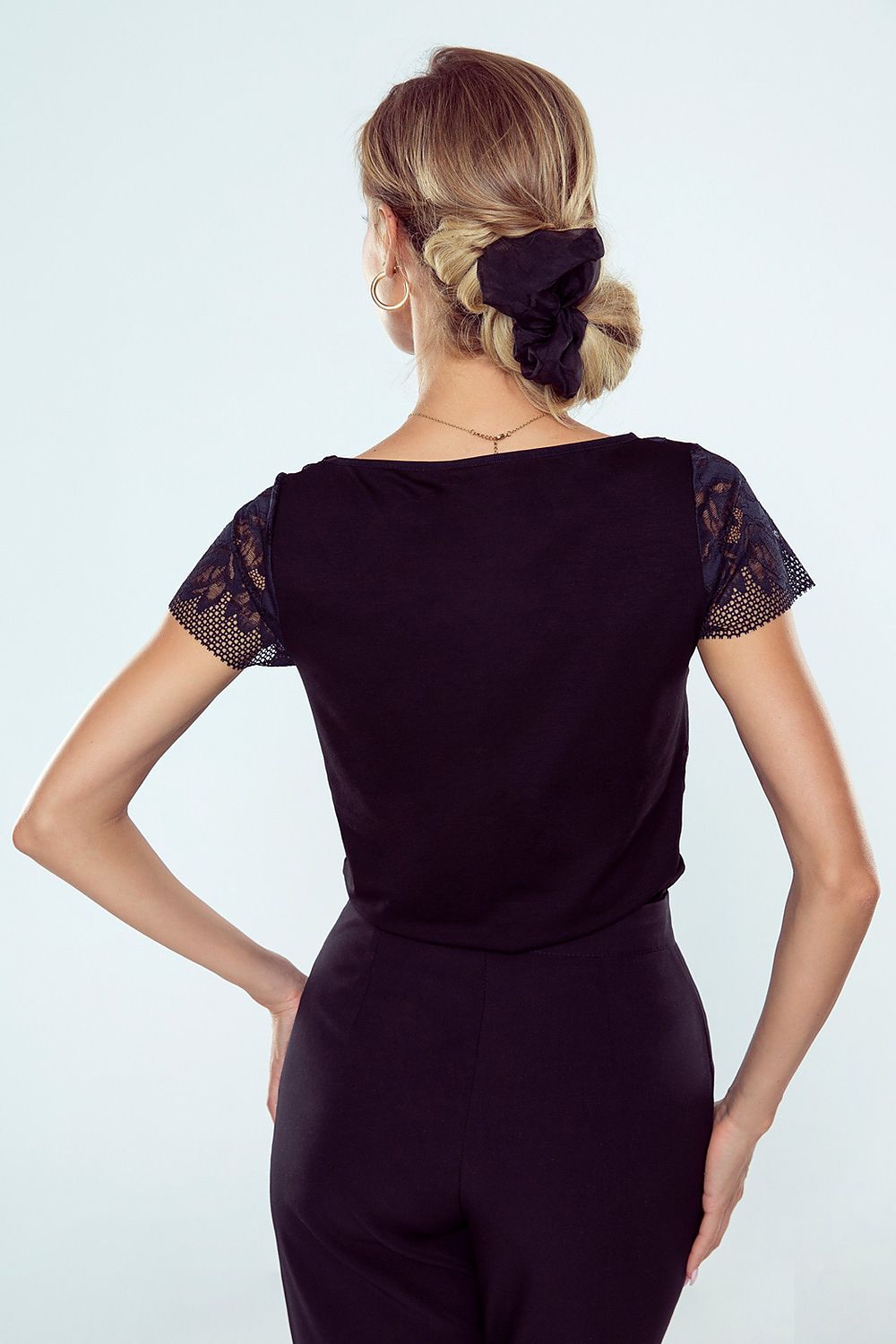 Back view of the sophisticated black blouse by Eldar Fashion, showcasing intricate lace cap sleeves and a sleek silhouette, ideal for upscale occasions.