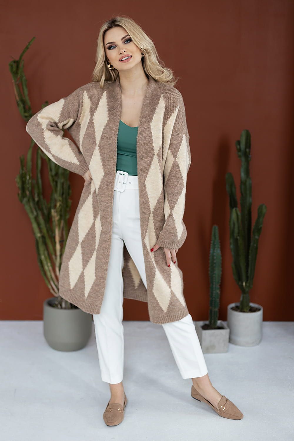 Elegant PeeKaBoo geometric cardigan in beige tones, model wearing with a green top and white trousers, ideal for chic layering.