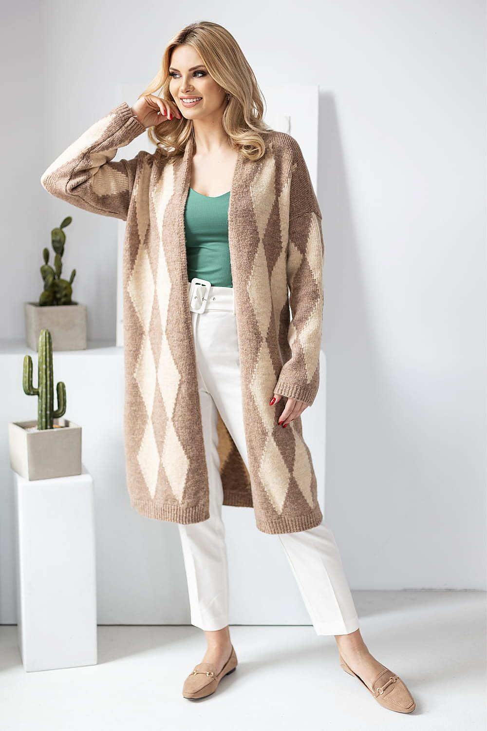 Stylish PeeKaBoo long sleeve cardigan featuring a geometric design, enhanced with a green top and white pants for a luxurious look.