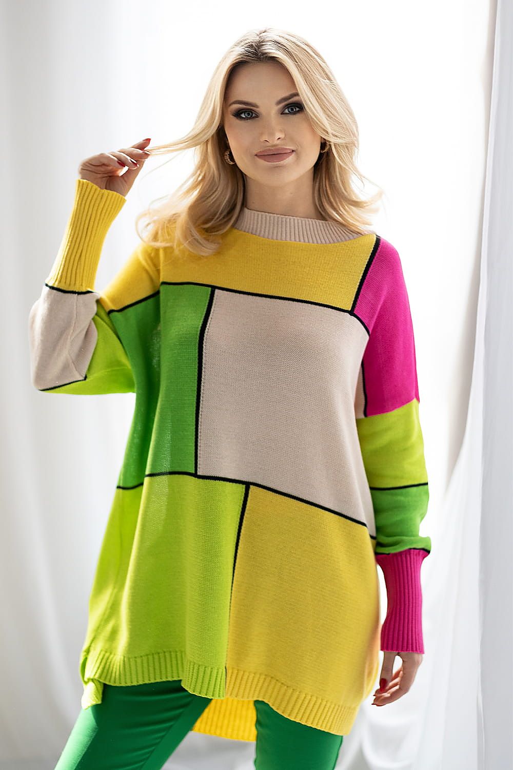 Elegant model wearing PeeKaBoo Colour Block Loose-Fitting Sweater in bright green, yellow, and pink. The relaxed fit and striking patterns shine in softly diffused light.