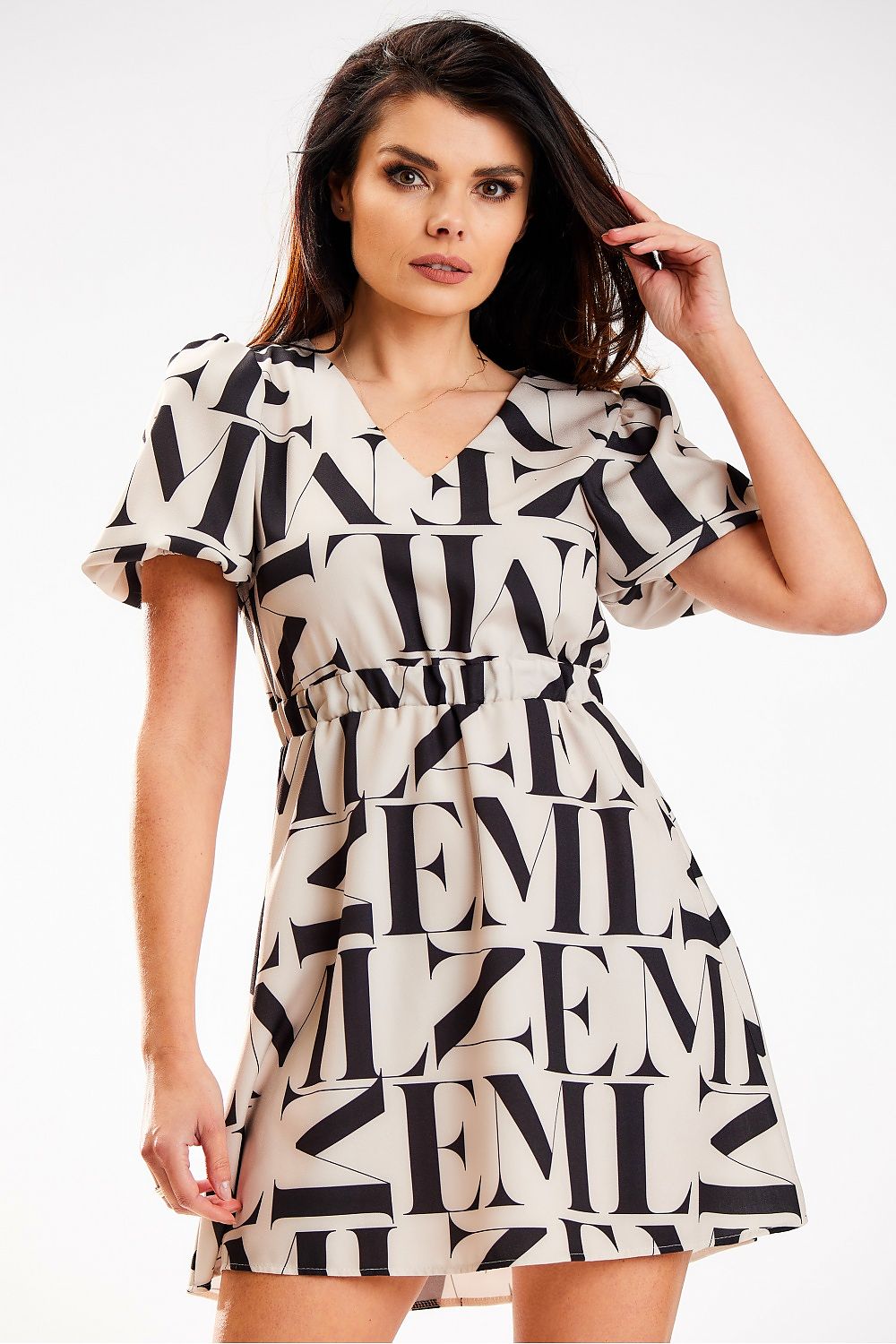 Elegant model showcasing a luxe beige crepe mini dress featuring a heart-shaped neckline and elastic waistband by Awama, accented with bold black lettering, perfect for fashionable summer outings.