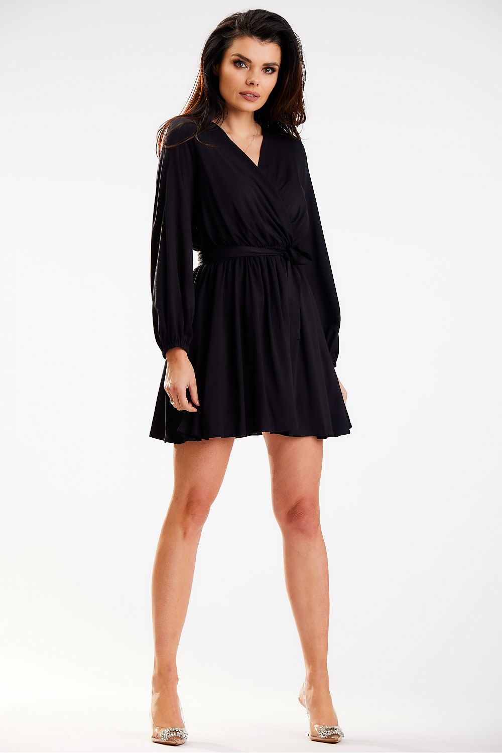 Stylish black mini dress by Awama, featuring long sleeves and a fitted waist, presented by a model in a confident pose.