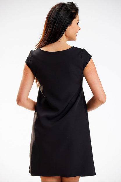 Elegant mini dress by awama featuring a loose trapezoidal cut and short sleeves, showcased on a model from the back, highlighting its sophisticated silhouette in black.