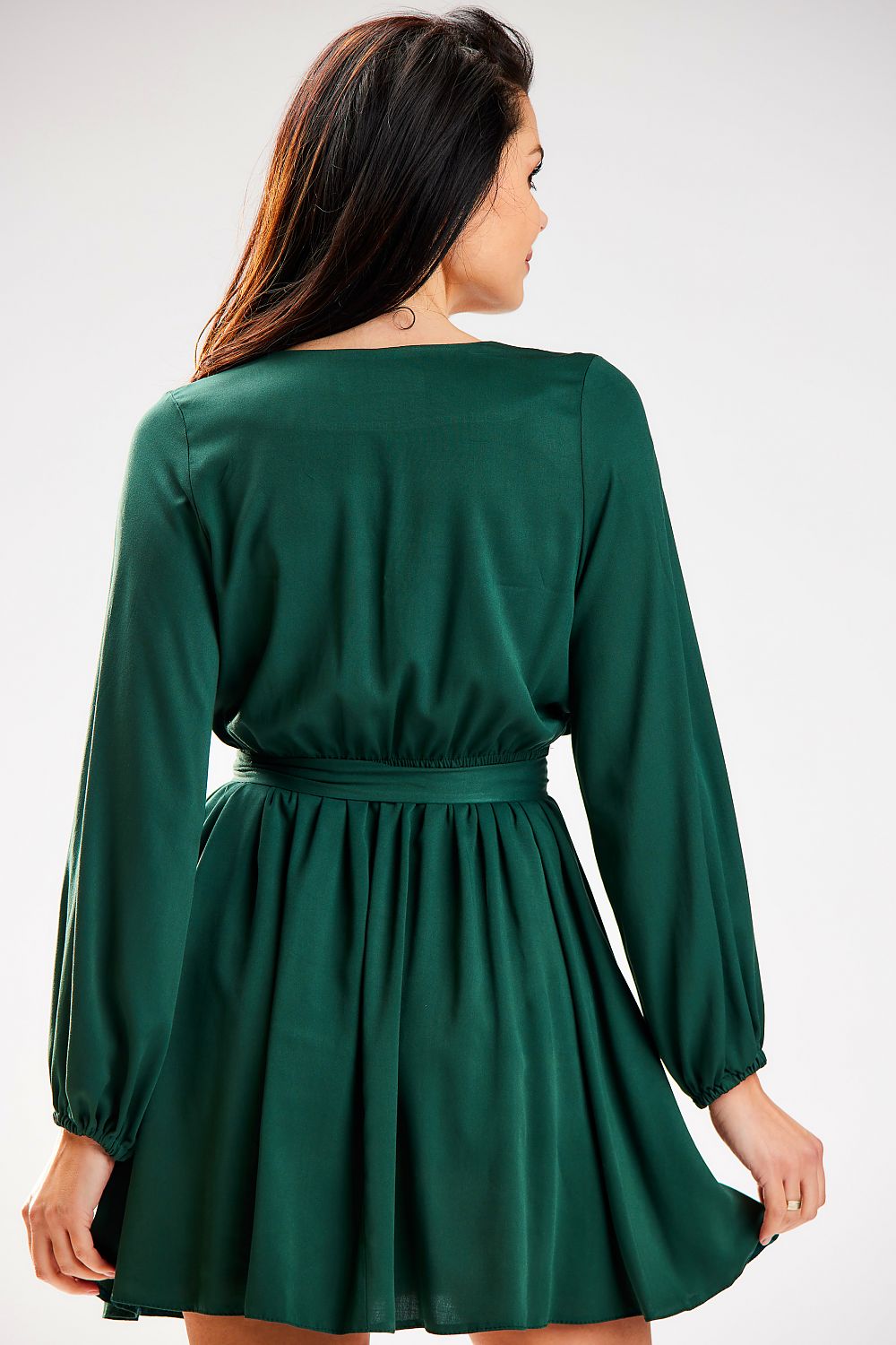 Elegant mini length dress from Awama featuring long sleeves and a cinched waist, showcased on a model from the back, in rich green fabric.