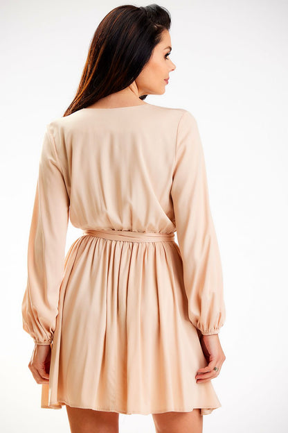 Elegant view of the back of a beige mini length dress with long sleeves and an elastic waist, showcasing the graceful flow and design by Awama, ideal for both formal and casual occasions.