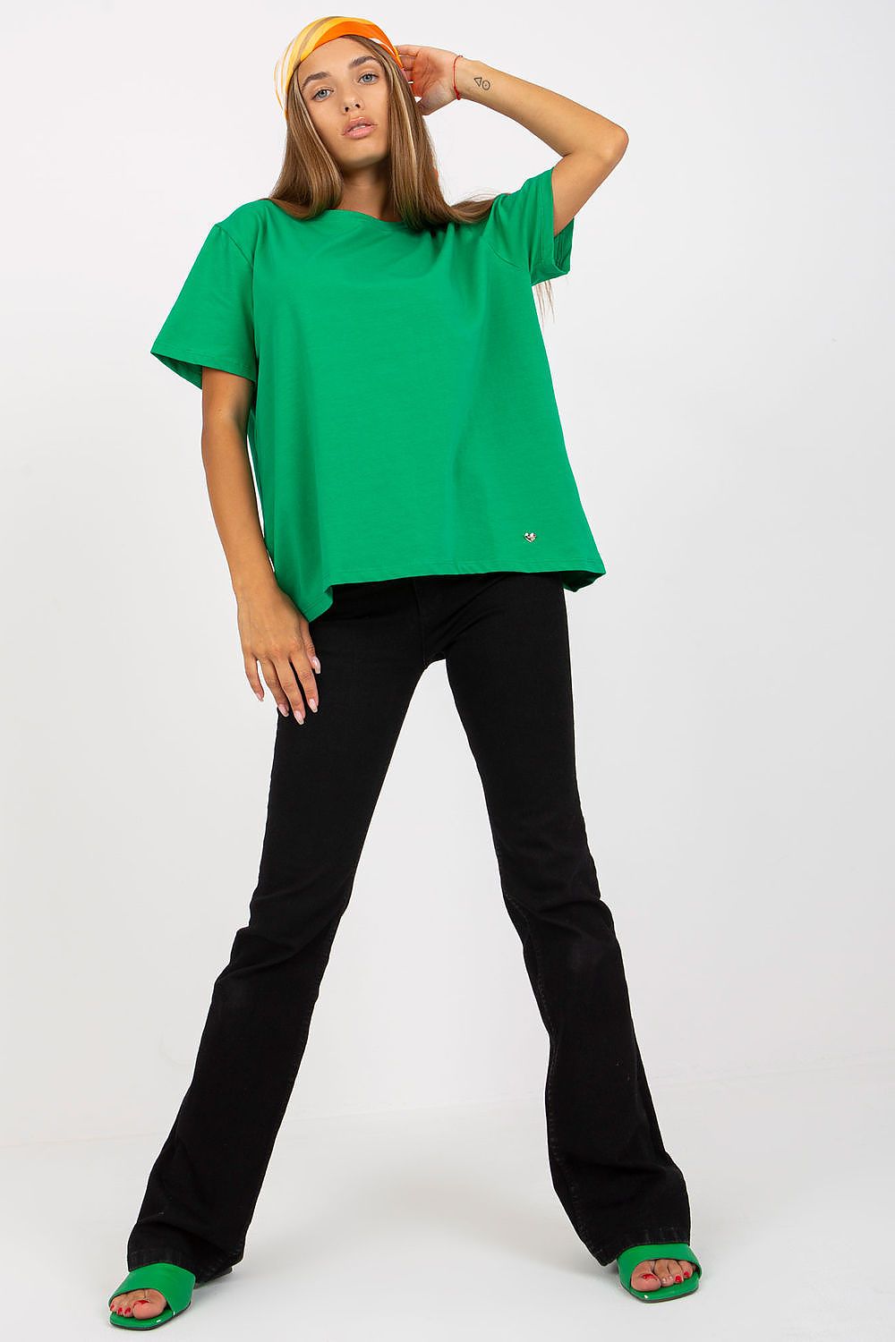 Front view of a Luxury Women's BFG T-Shirt in vibrant green, paired with stylish black flared pants, highlighting the relaxed fit and chic design.