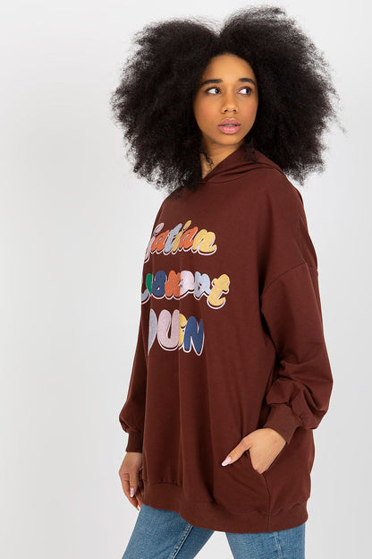 Elegant women's hooded sweatshirt by Fancy in brown, model showcasing the side view, adorned with colourful front inscription.