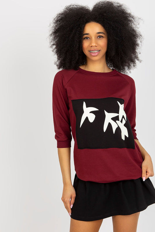 Sophisticated model showcasing the elegant 2-piece sweatshirt set by Fancy, featuring a burgundy sweatshirt with decorative print and a stylish black skirt. Perfect for casual chic attire.