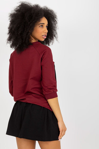 Back view of a model in the elegant 2-piece sweatshirt set by Fancy, demonstrating the sleek design of the burgundy sweatshirt and its stylish black skirt, perfect for fashionable wear.