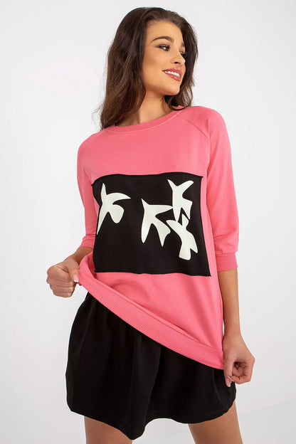 Chic pink sweatshirt set by Fancy featuring a captivating decorative print round neckline and a flattering black skirt, perfect for upscale casual occasions.