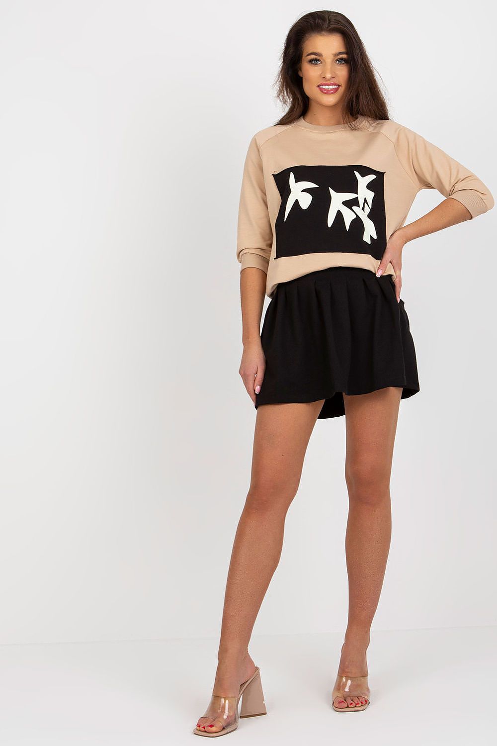 Sophisticated model in a beige sweatshirt and black flared skirt, exuding elegance in luxurious attire by Fancy.