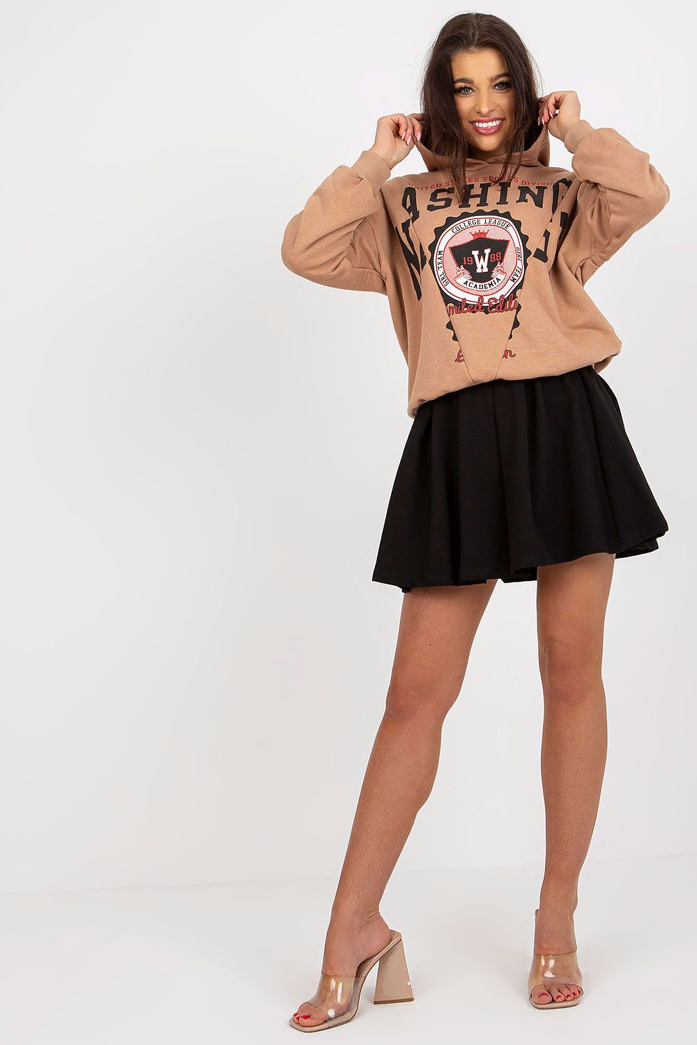 Model joyfully posing in a luxury cotton spandex sweatshirt and flared skirt set by Fancy, showcasing the brown hoodie and classic black skirt ensemble.