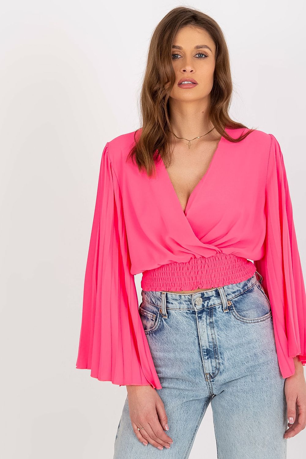 Elegant Italy Moda blouse featuring pleated long sleeves and an envelope neckline, styled in a vibrant pink colour, paired with high-waisted denim shorts.