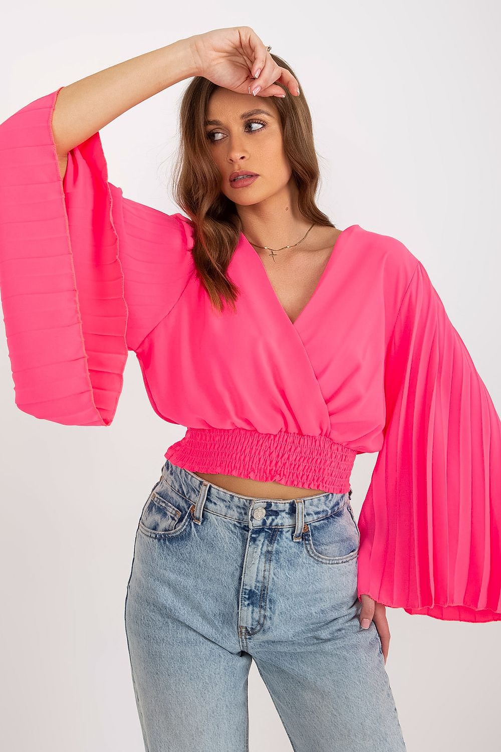 Chic Italy Moda blouse in pink with dramatic pleated long sleeves and an envelope neckline, elegantly styled with high-waisted denim shorts.