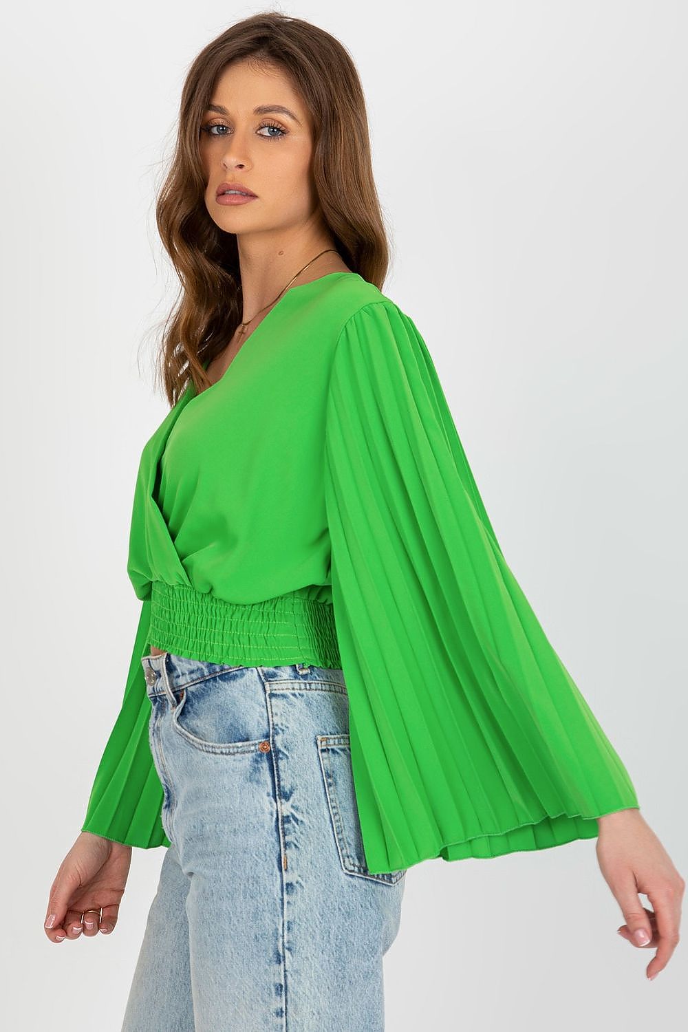 Side view of an elegant green blouse by Italy Moda, showcasing pleated sleeves and a sophisticated envelope neckline, paired beautifully with high-waisted jeans.