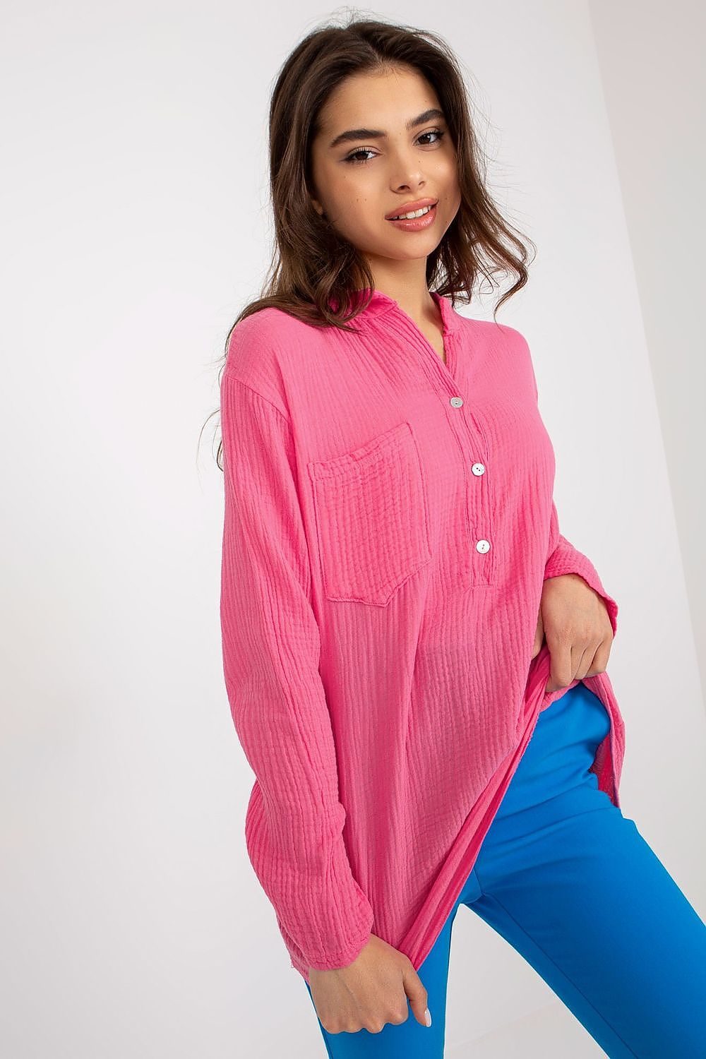 Och Bella elegant cotton muslin blouse in vibrant pink with a v-neck, long sleeves, and a stylish front pocket, showcased in a luxurious setting.
