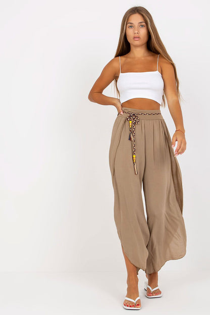 Trendy high-waist trousers in a taupe shade from Och Bella, elegantly styled with a decorated waist tie, modeled with a chic white top for a sophisticated look.