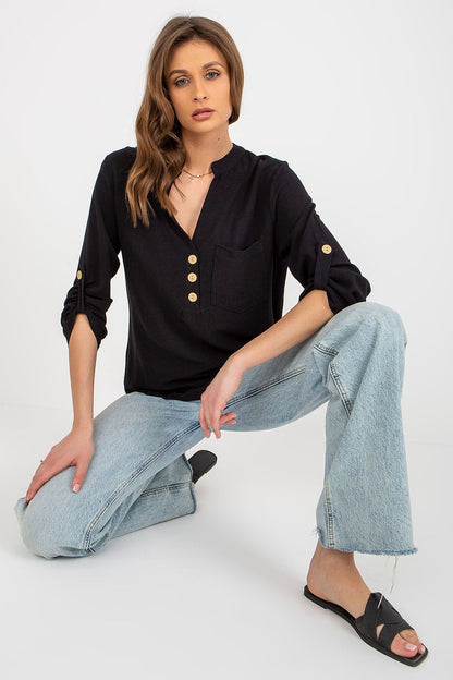 Fashionable pose in a black Rue Paris blouse made from a soft cotton blend, featuring a heart-shaped neckline and stylish buttons, combined with trendy jeans.