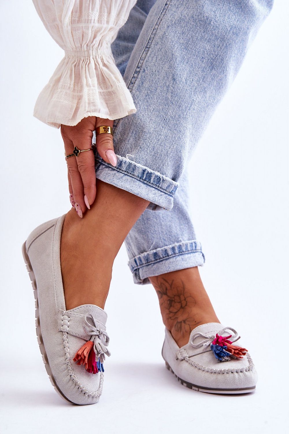 Step in Style eco-suede moccasins for women shown with rolled denim, showcasing comfort and sophistication with decorative tassels and bow.