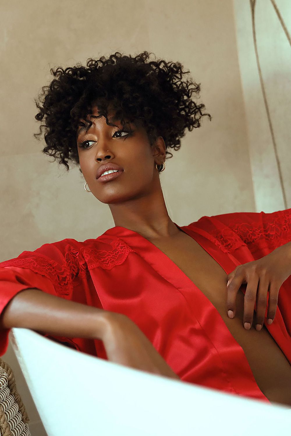 Elegant DKaren satin bathrobe in red with delicate lace trim, showcased on a model with curly hair, exuding luxury and sensuality, perfect for luxurious comfort and style.