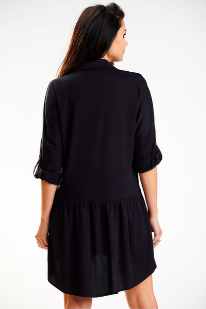 Sophisticated black loose shirt dress with a trapezoidal collar and gold round buttons by Awama, featuring rolled-up sleeves and a flared hem for an elegant silhouette.