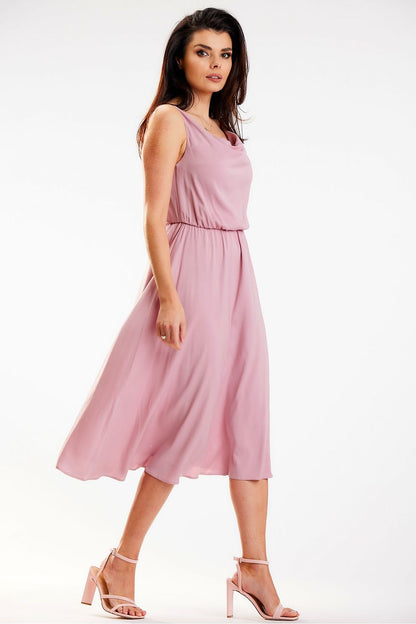 Side view of the luxurious Awama midi dress in delicate pink fabric, showcasing a flowing silhouette and crinkled neckline, elegantly styled by a model.