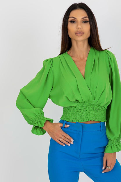 Stylish model showcasing an elegant long sleeve blouse with envelope neckline in vibrant green, paired with chic blue trousers by Italy Moda.