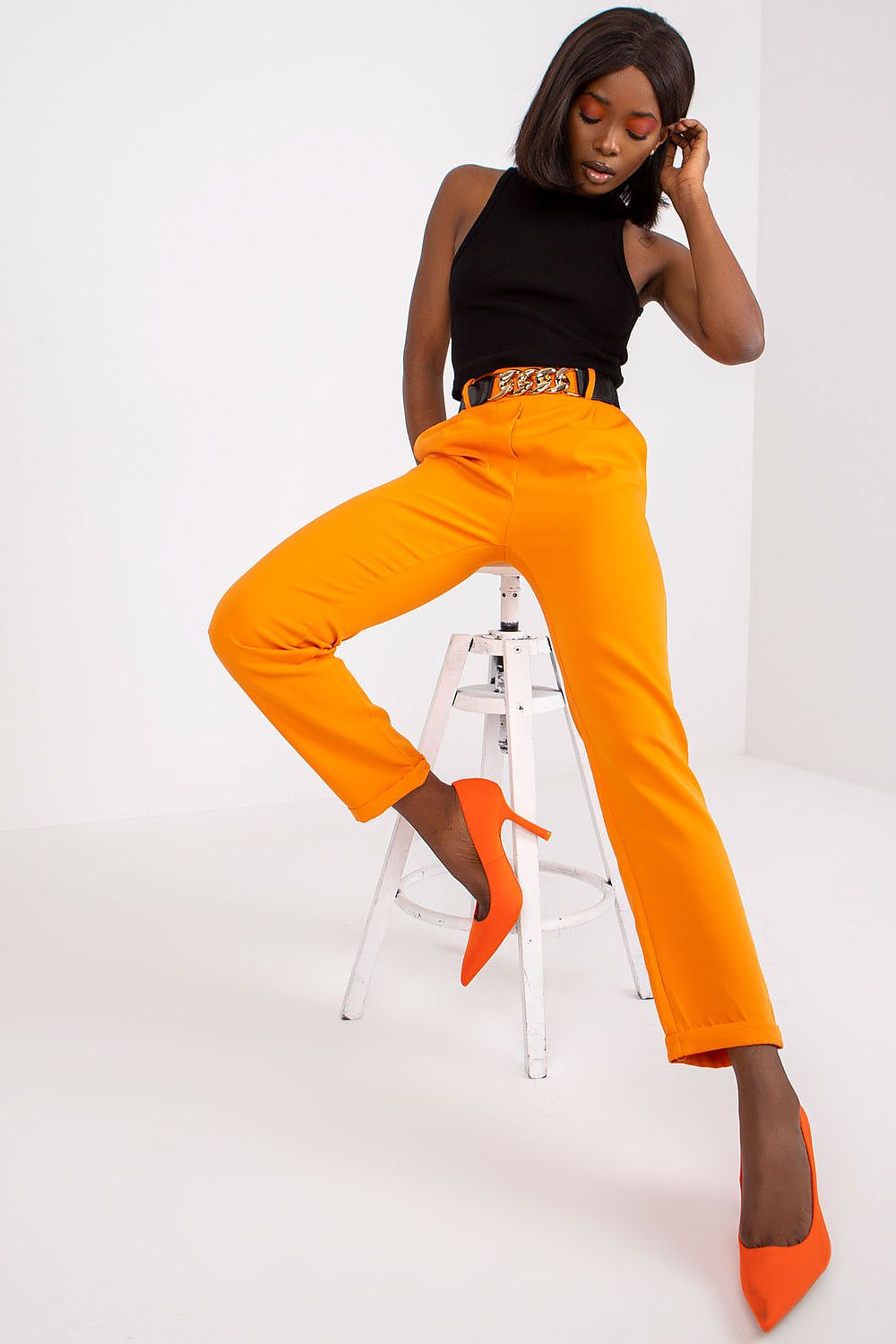 Sophisticated orange high rise trousers paired with a statement belt, perfect for date night and fashionable outings, by Italy Moda.