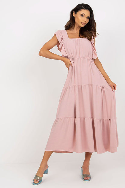 A model showcasing an elegant loose-fit long summer dress by Italy Moda, featuring a square neckline and sleeveless design, in soft pink fabric with ruffled sleeves, perfect for stylish summer occasions.
