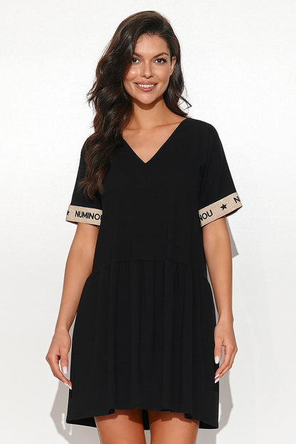 Elegant woman wearing a chic black flared dress by Numinou, featuring short sleeves with distinctive branding and a flattering v-neckline. The lightweight sweatshirt fabric adds a luxurious feel, perfect for both casual and sophisticated occasions.