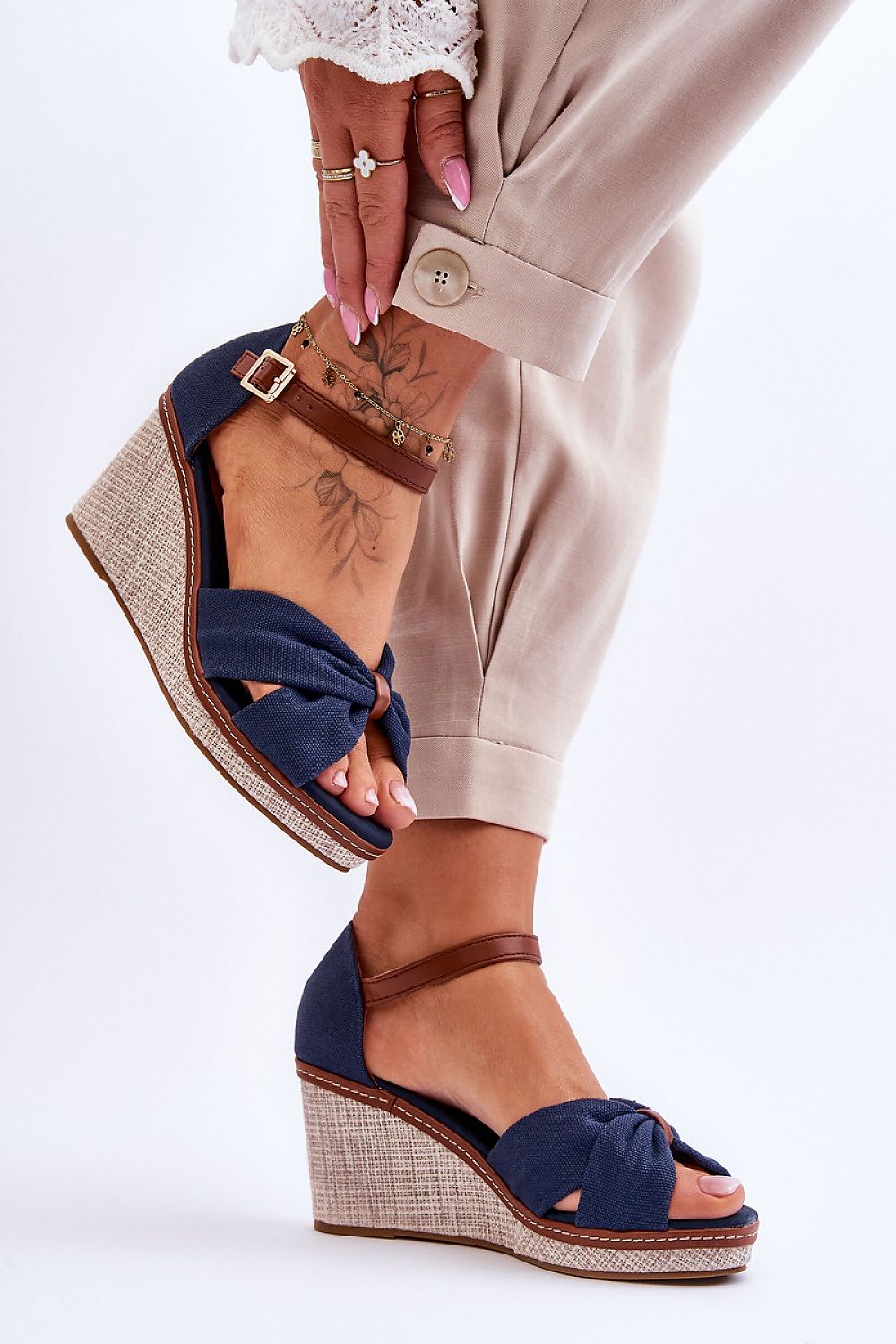 Step in Style elegant navy sandals with a 8cm wedge heel, adorned with a knotted design and enhanced with ankle straps, elegantly styled with tailored trousers.