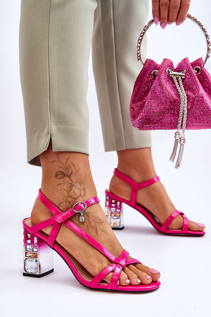 Stylish pink stiletto heel sandals by Step in Style, featuring adjustable buckle closures and sparkling stone decorations, showcased with tailored trousers.