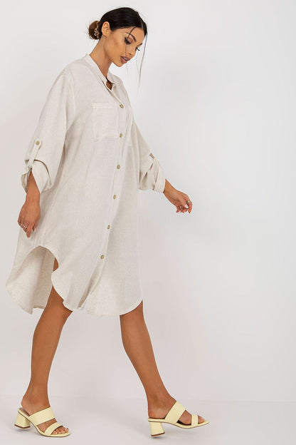 Chic and sophisticated shirt-cut dress by Och Bella, showcasing a light fabric design, long sleeves, and front pockets, complemented by elegant sandals.