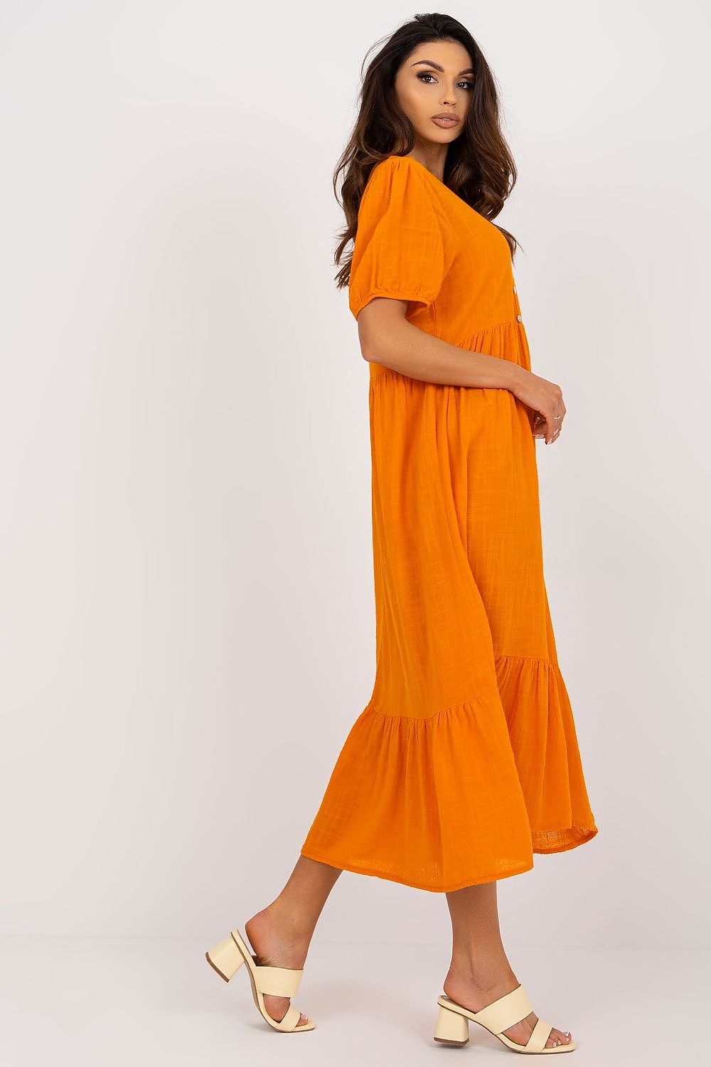 Stylish profile view of the Och Bella short sleeve daydress in vibrant orange, showcasing its ruffled hem and elegant silhouette.