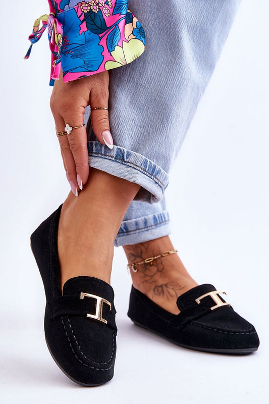 Chic black slip-on moccasins from Step in Style, adorned with a decorative strap, perfectly paired with vibrant floral attire and denim.