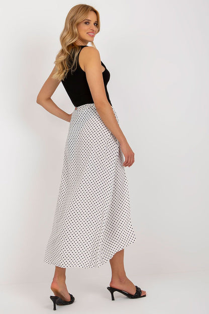 Luxurious asymmetrical long skirt by Rue Paris featuring decorative slits and elegant navy polka dots on white fabric.