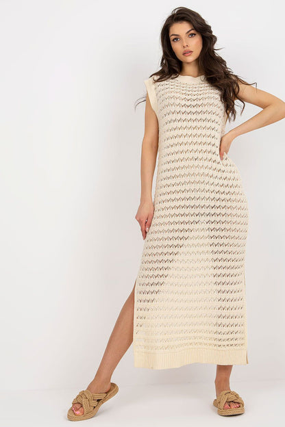 Model wearing Badu's luxury openwork long knit beach dress, demonstrating its fit and flow at the coastline.