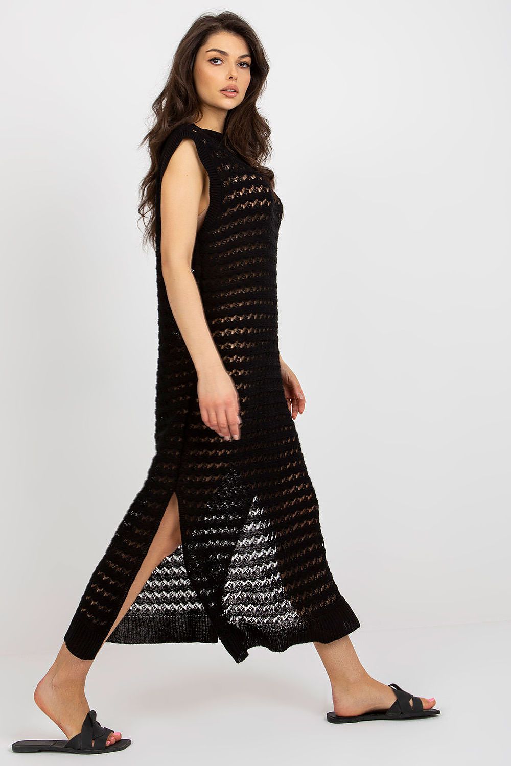 Badu's long knit beach dress with intricate openwork design and chic side slits, combining comfort and sophistication.