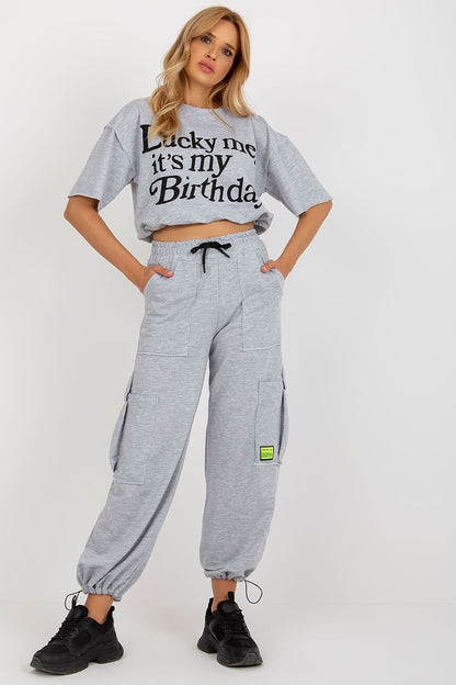 Badu Tracksuit Set displayed elegantly on a model, highlighting the sophisticated design of the short sleeve blouse and tailored long pants with slip pockets.