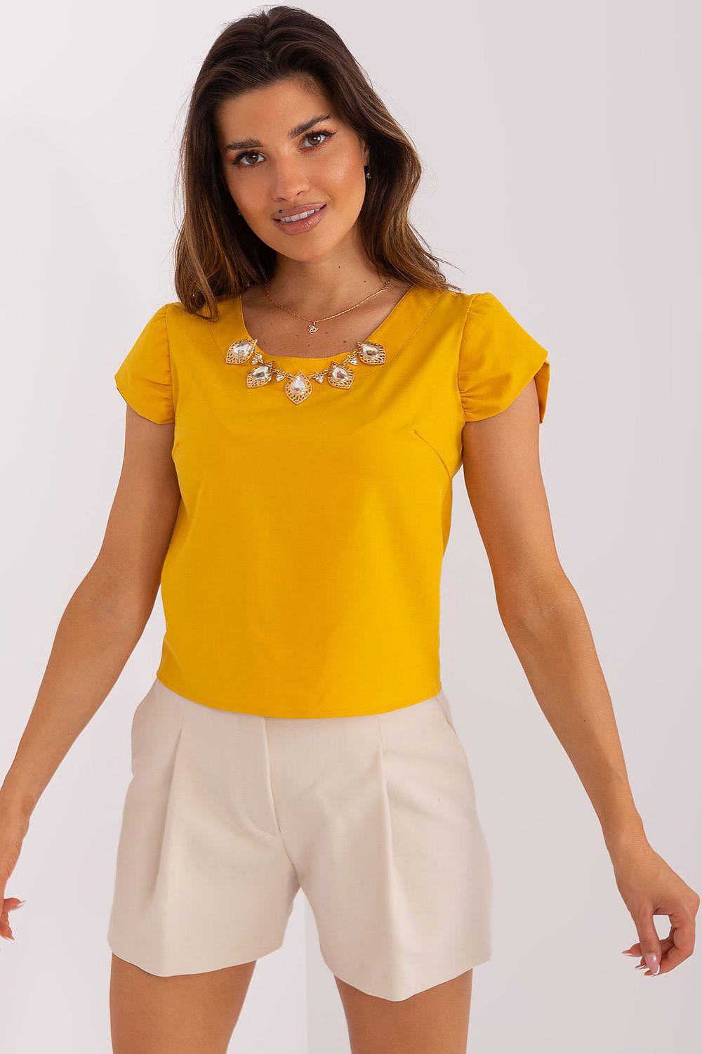 Elegant Lakerta short-sleeved blouse featuring a round neckline and luxurious front jewelry embellishment.