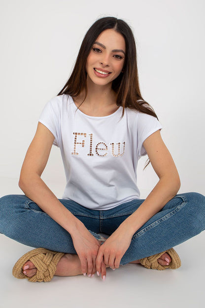 Stylish women's casual t-shirt from Fancy, showcasing a detailed cut-out inscription 'Flew'. The model poses seated, exuding luxury in this chic white top paired with distressed denim.