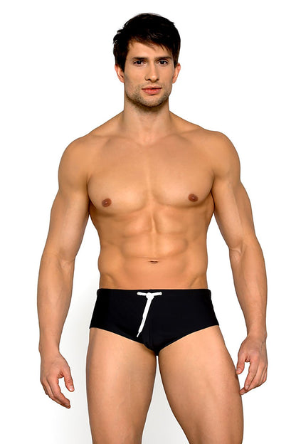 Model wearing Lorin luxury lined swimming trunks on the beach, displaying a trendy look and exceptional fit with an elastic waistband that combines style and comfort.