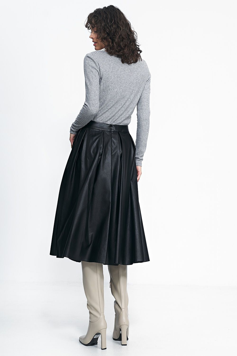 Stylish autumn outfit featuring the Luxury Midi Pleated Skirt by Nife, paired with high boots and a thick sweater, exemplifying sophisticated seasonal fashion.