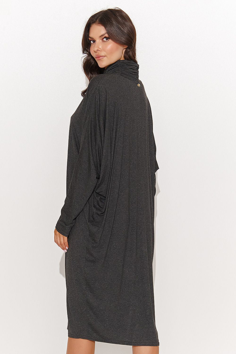 The versatile oversize turtleneck dress by Numinou, styled with boots, demonstrating its all-day comfort and fashionable appeal for both work and leisure.