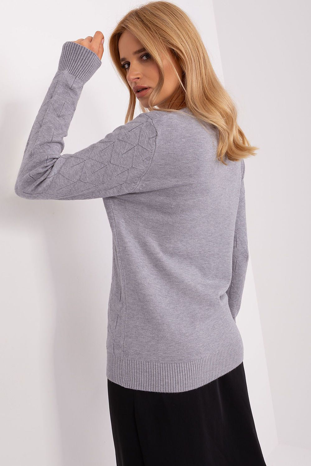 A luxurious women's sweater displayed on a clothing rack, highlighting its elegant cut and long sleeve design for fashionable layering.