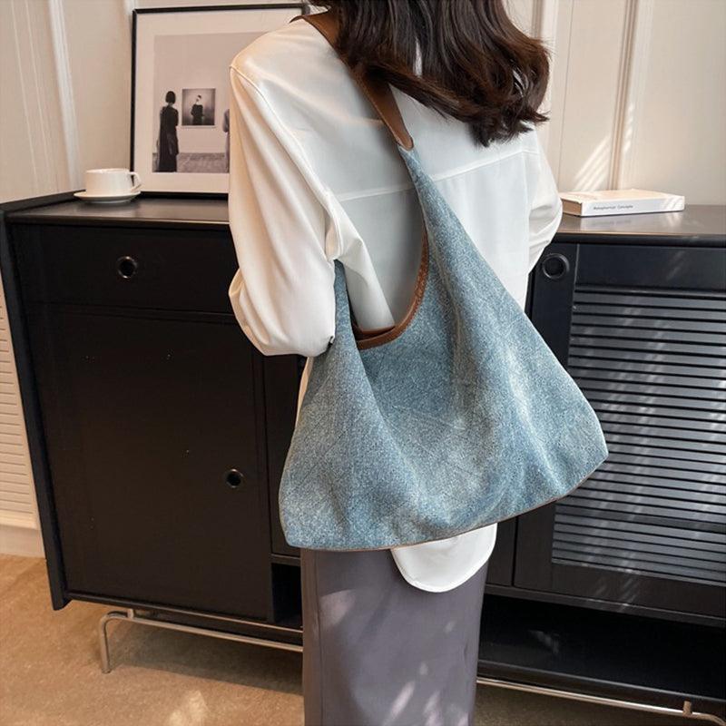 Luxury denim large shoulder handbag in dark blue, perfect for stylish casual and business use, showcased in an elegant setting.