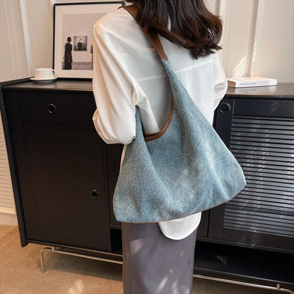 Luxury denim large shoulder handbag in dark blue, perfect for stylish casual and business use, showcased in an elegant setting.