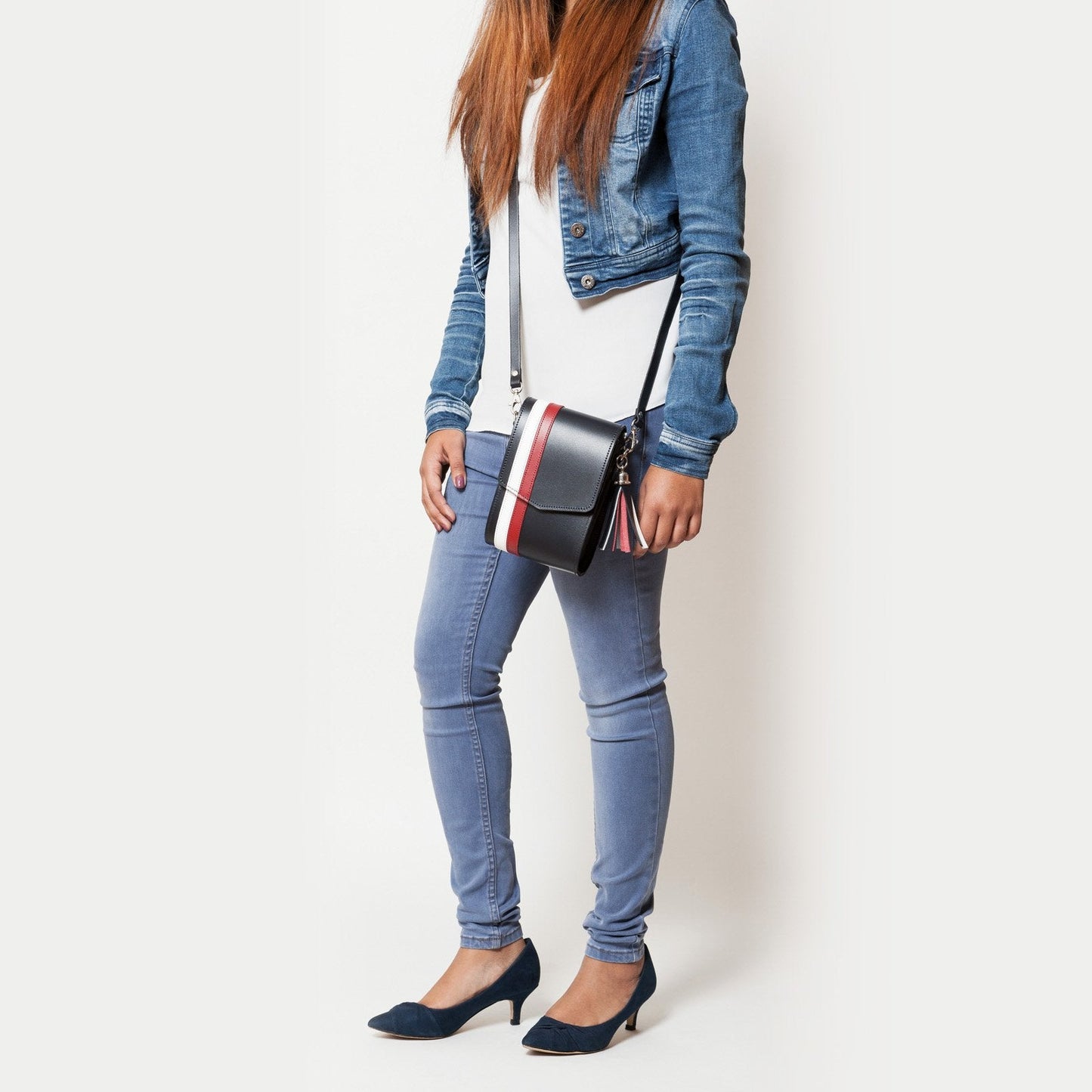 Versatile luxury navy blue leather phone bag worn as a clutch, highlighting its adjustable strap and spacious design for essentials.