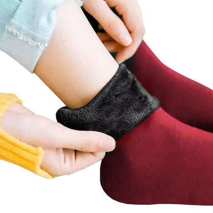 Luxury Women's Velvet Thermal Socks: Close-up image of hands adjusting rich, red wine thermal socks featuring luxurious velvet.