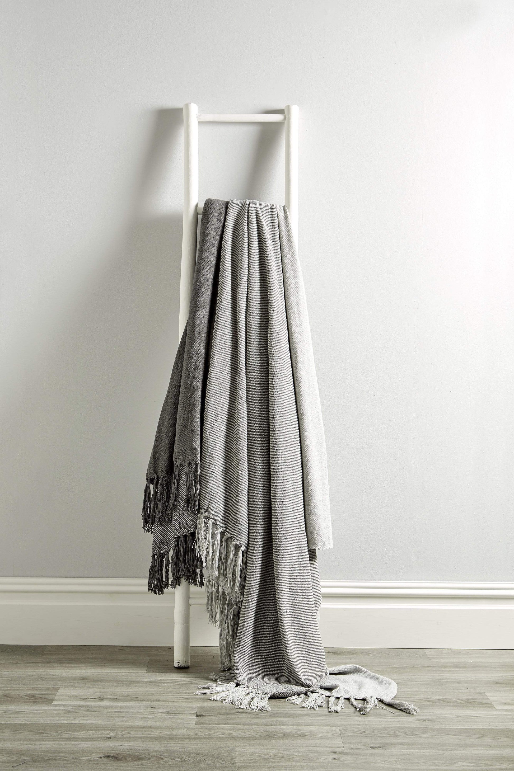 Close-up of the luxurious texture of handwoven Indian cotton throw blanket with classic check pattern and decorative tassels, perfect for enhancing any living space.